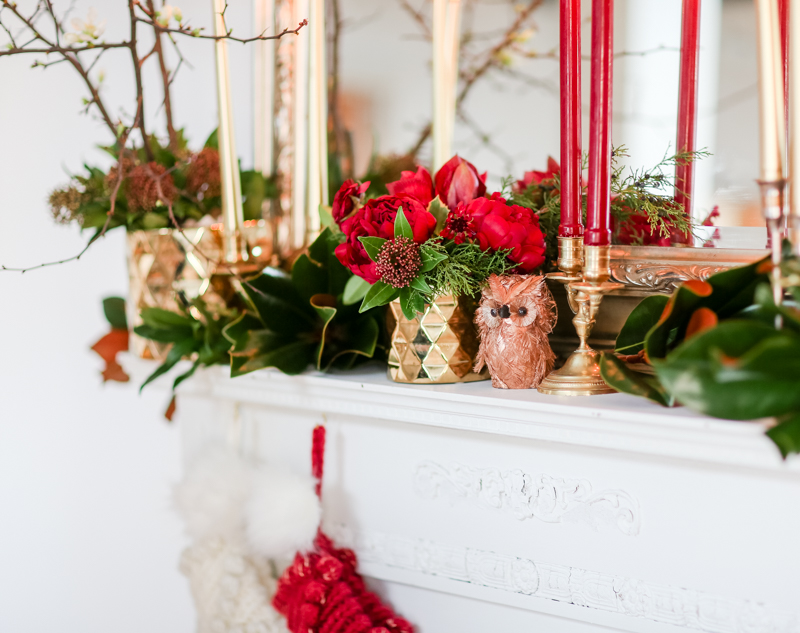 Christmas Flowers by E.H. Floral on a mantle with candles